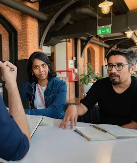 A seated group is discussing a topic with notepads in front of them.